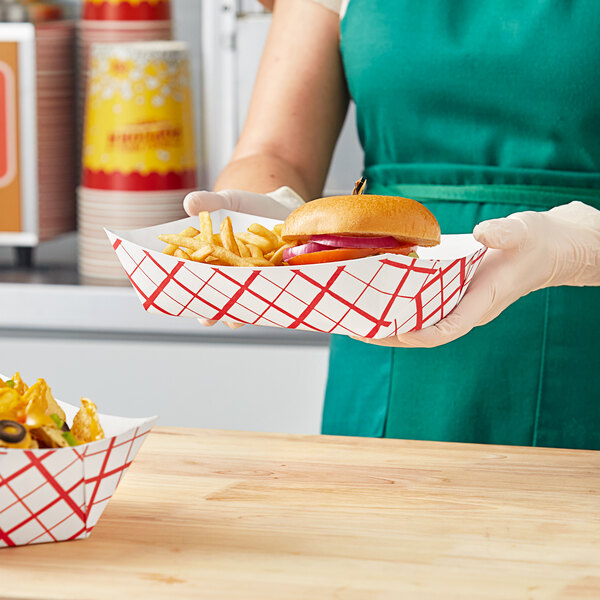 A woman holding a Southern Champion paper food tray with a hamburger and fries.