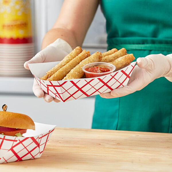 A woman holding a Southern Champion red checkered paper food tray of fried food.