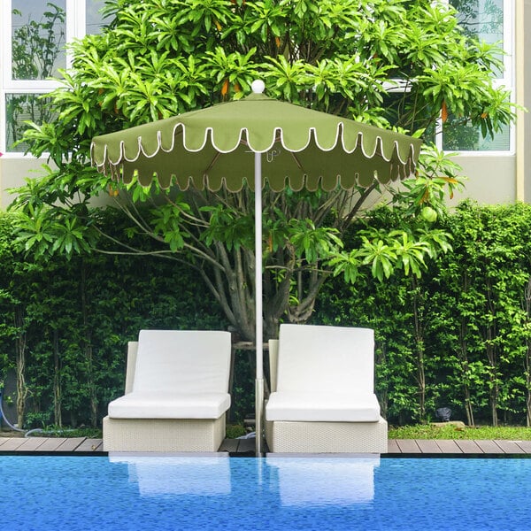 A spectrum cilantro green patio umbrella with a scalloped edge over two white chairs with cushions.