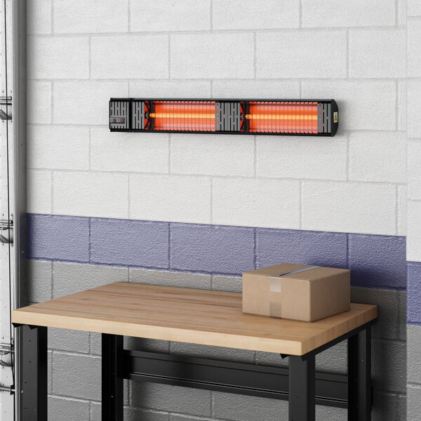 A Boltic black electric infrared heater on a wood table in a room.