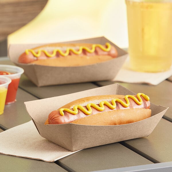 Two hot dogs in Southern Champion paper food trays with mustard.