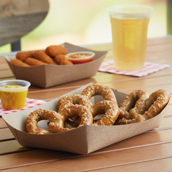 A Southern Champion Kraft lunch tray holding pretzels and sausages on a table.