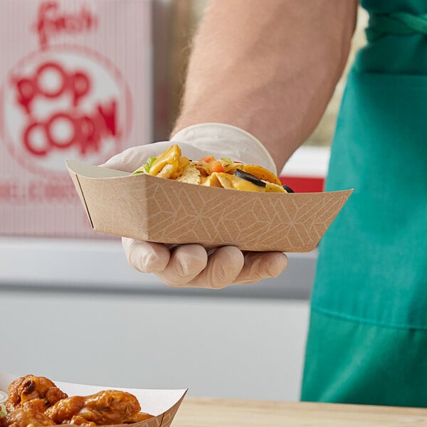 A person holding a Southern Champion paper food tray filled with food on a counter.