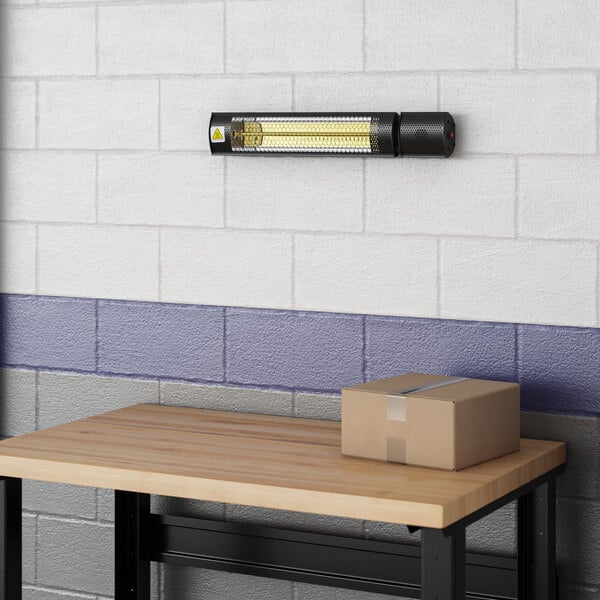A Boltic black electric infrared heater mounted on a wall above a table in a bar.