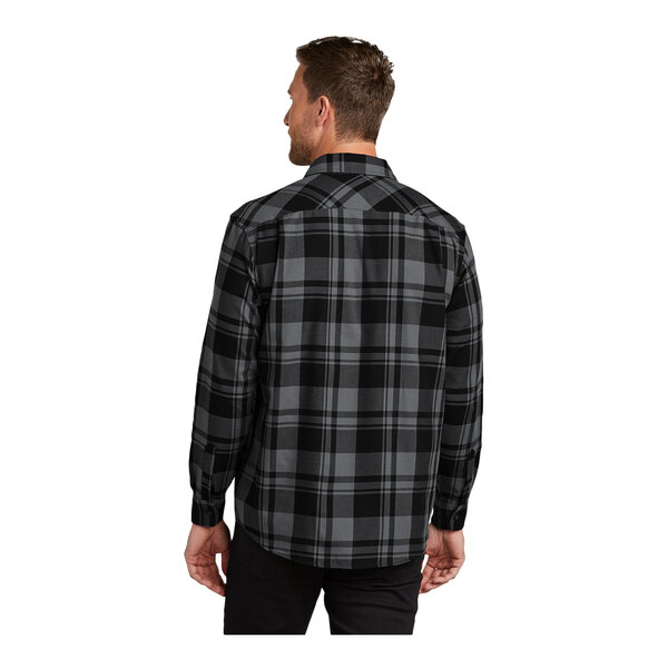 A man wearing a black and grey plaid Port Authority flannel shirt.