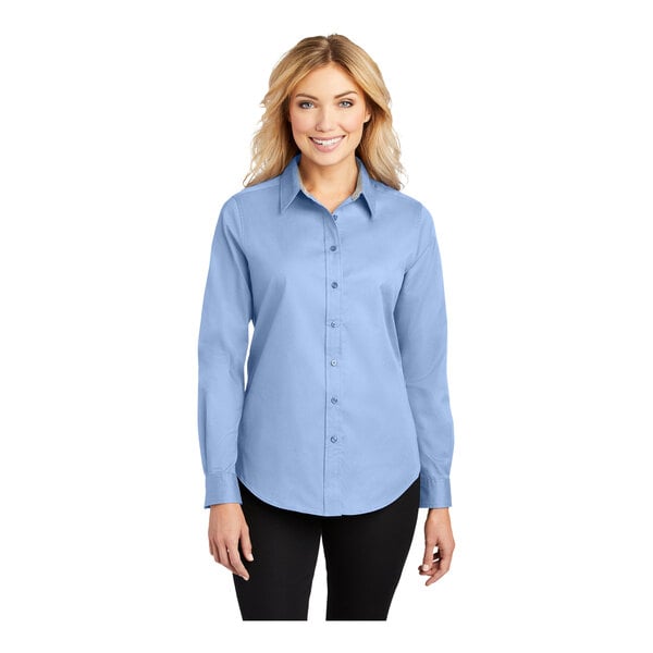 A woman wearing a light blue Port Authority long sleeve button-up shirt.