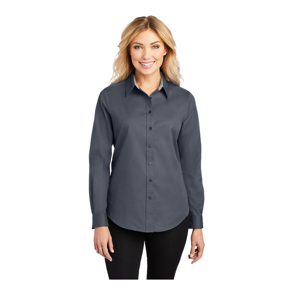 A woman wearing a Port Authority steel gray and light stone long sleeve poplin shirt.