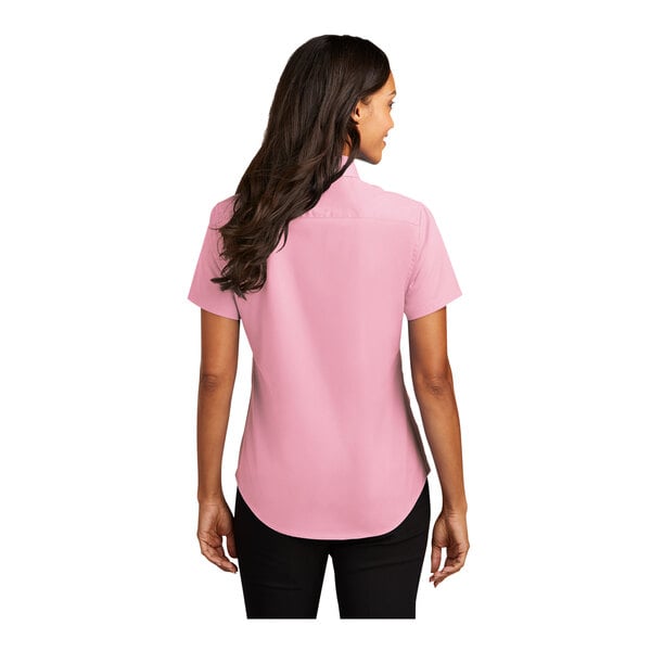 A woman wearing a Port Authority light pink short sleeve dress shirt.