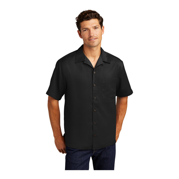 A man wearing a black Port Authority short sleeve camp shirt.