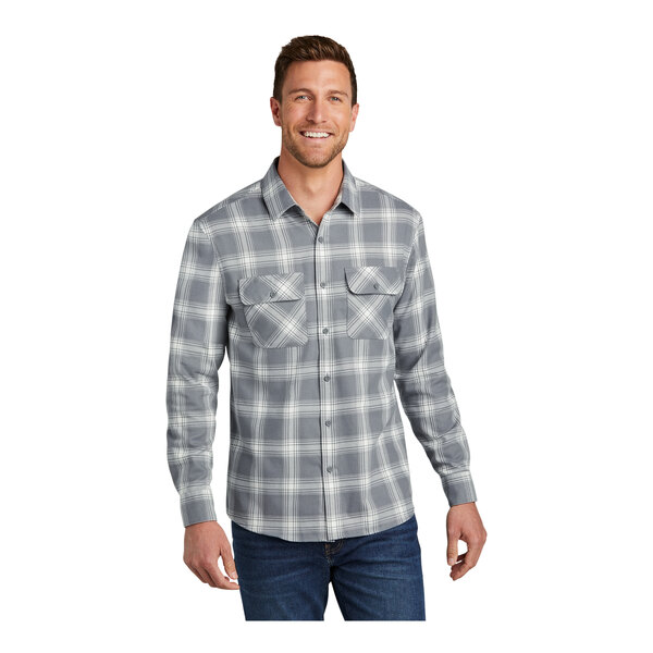 A man wearing a Port Authority gray and cream plaid flannel shirt with the sleeves rolled up.