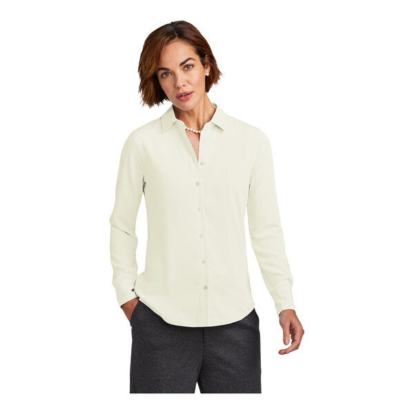 A woman with short brown hair wearing a Brooks Brothers off white long sleeve full-button satin blouse.