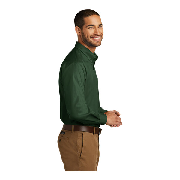 A man wearing a deep forest green Port Authority long sleeve poplin dress shirt.