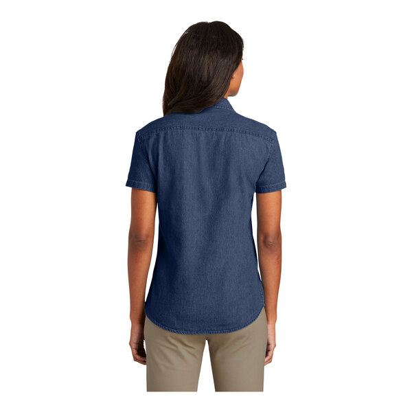 A woman wearing a Port & Company short sleeve denim button-down shirt in blue.