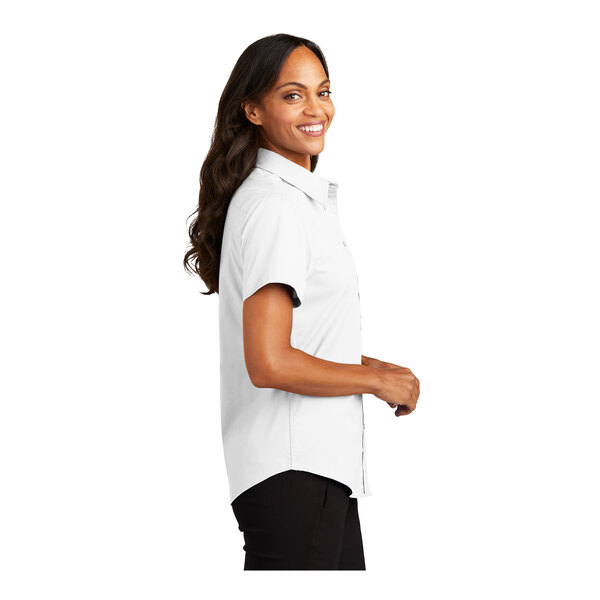 A woman wearing a Port Authority white short sleeve button down dress shirt.