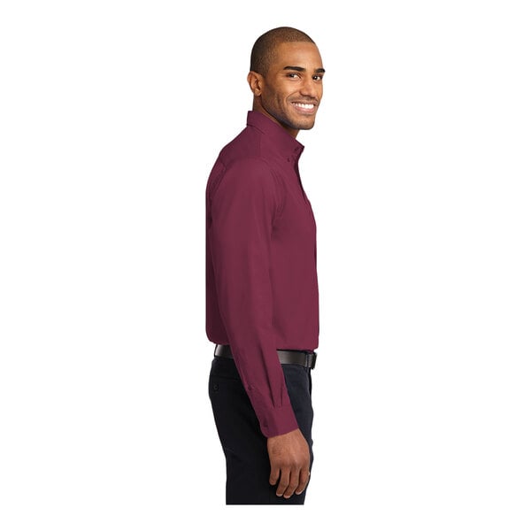 A man wearing a burgundy and light stone Port Authority dress shirt.