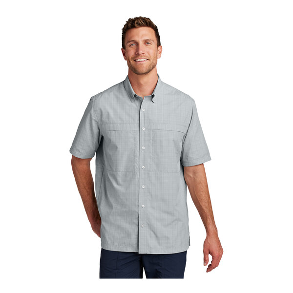 A man wearing a Port Authority crosshatch plaid short sleeve shirt in white and gray.