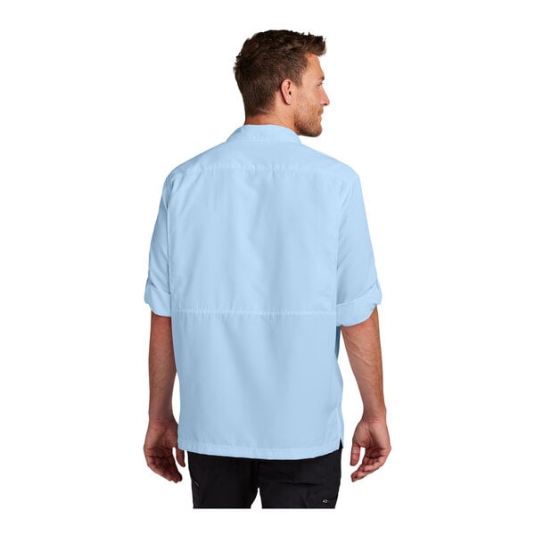 A man wearing a light blue Port Authority long sleeve shirt.