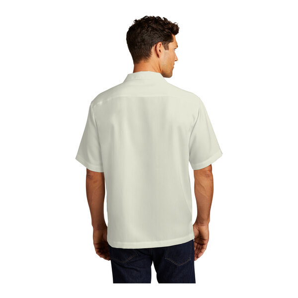 A man wearing a white Port Authority short sleeve shirt with a pocket.