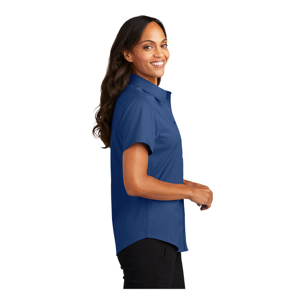 A woman wearing a royal blue and navy Port Authority dress shirt with short sleeves.