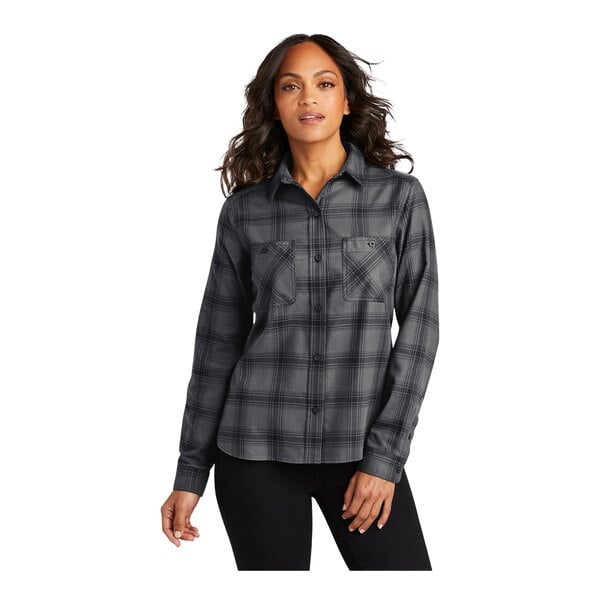 A woman wearing a Port Authority long sleeve plaid flannel shirt with black and gray open plaid design.