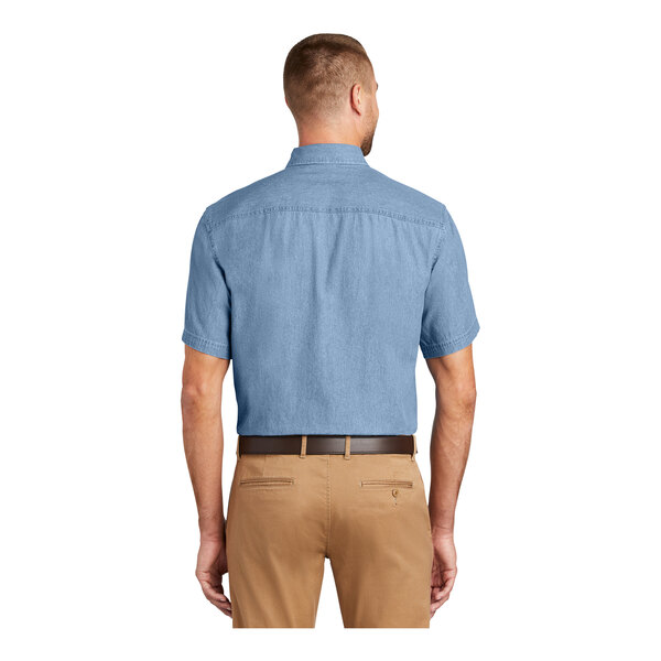 A man wearing a faded blue Port & Company short sleeve denim button-down shirt.