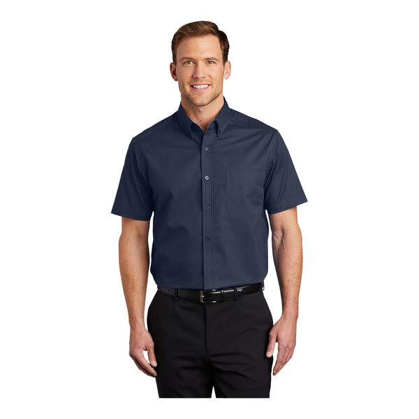 A man wearing a Port Authority navy and light stone short sleeve dress shirt.