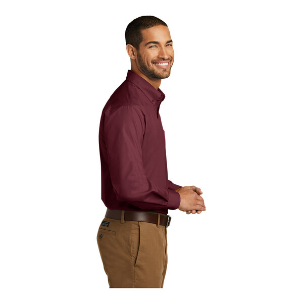 A man wearing a burgundy Port Authority long sleeve poplin dress shirt.