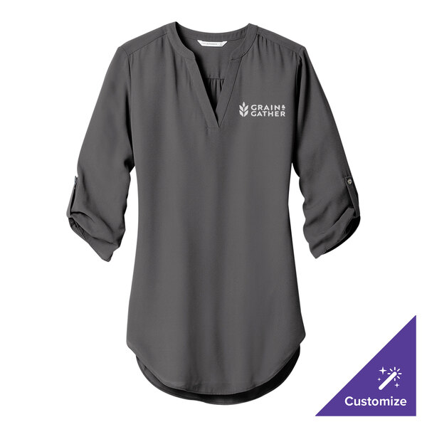 A Port Authority sterling gray women's tunic blouse with white custom text on the counter.