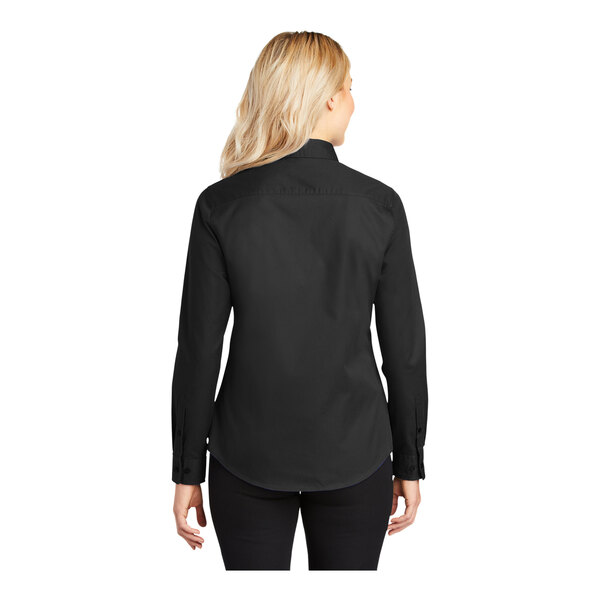 A woman wearing a black Port Authority long sleeve button down shirt.