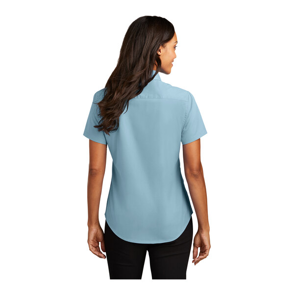 A woman wearing a light blue Port Authority short sleeve button down dress shirt.