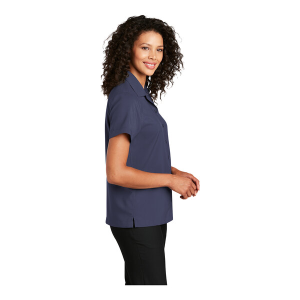 A close-up of a woman wearing a Port Authority True Navy performance staff shirt.