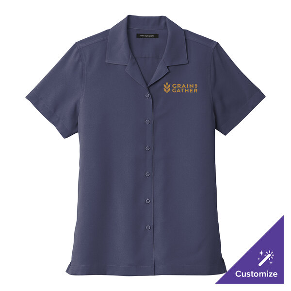 A women's navy blue short sleeve staff shirt with gold embroidery on the logo.