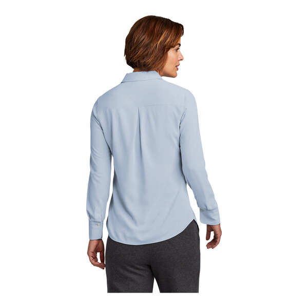 A woman wearing a Brooks Brothers blue long-sleeved shirt with buttons.