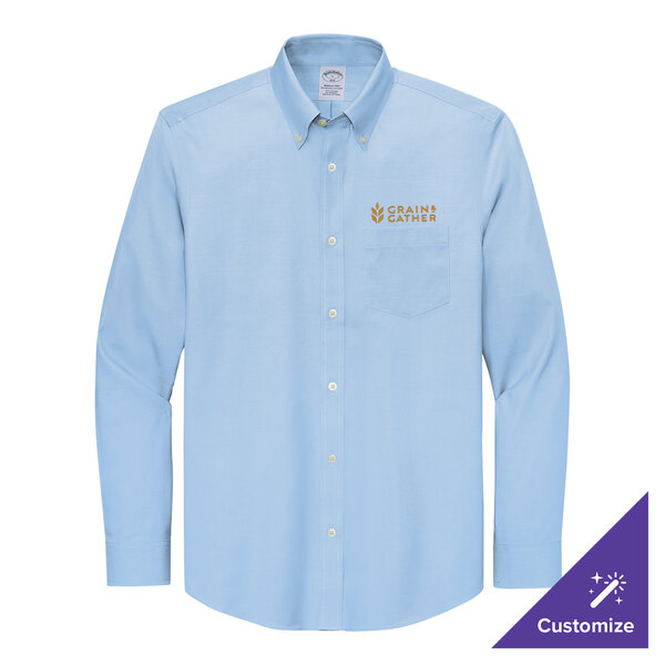 A long sleeved light blue button up shirt with gold embroidery on the chest.
