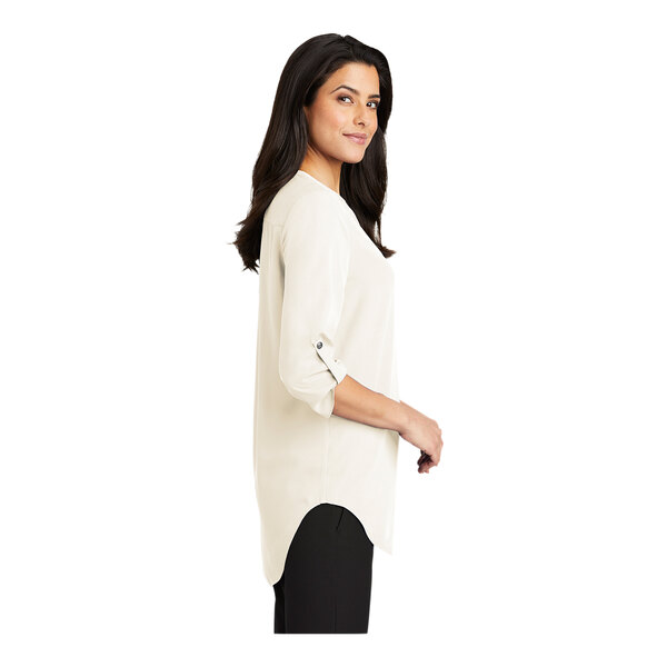 A woman wearing a Port Authority ivory chiffon short sleeve blouse.