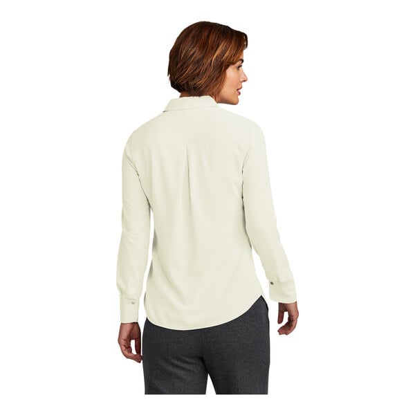 A woman wearing a Brooks Brothers off white long sleeve full-button satin blouse.