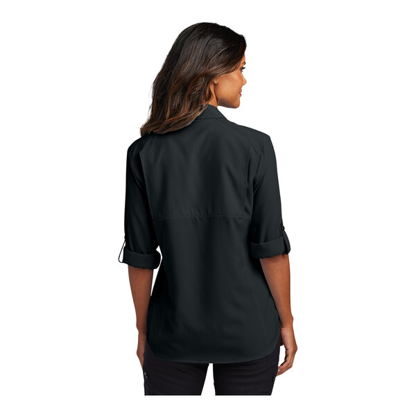 A woman wearing a black short sleeve Port Authority shirt.