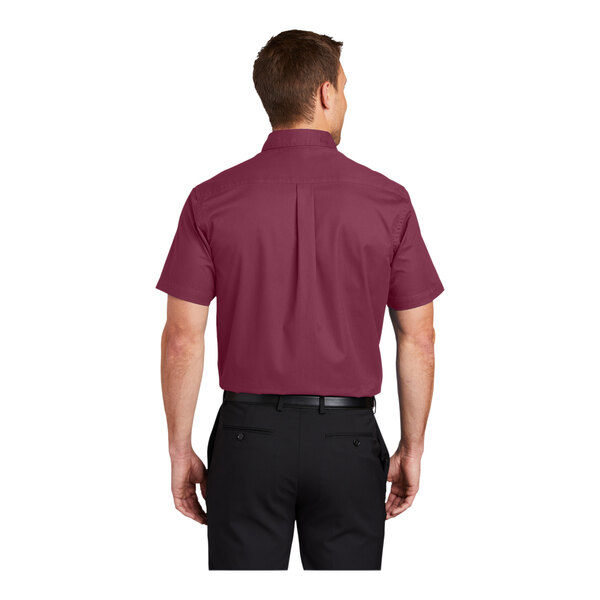 A man wearing a burgundy and light stone Port Authority dress shirt with short sleeves.