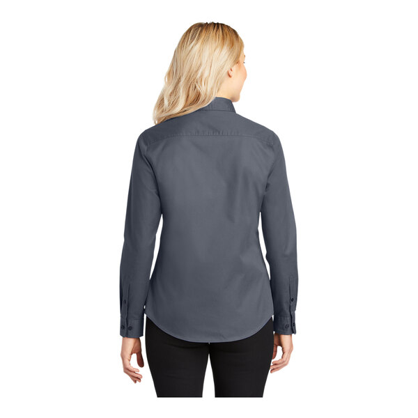 A woman wearing a Port Authority steel gray long sleeved poplin dress shirt.