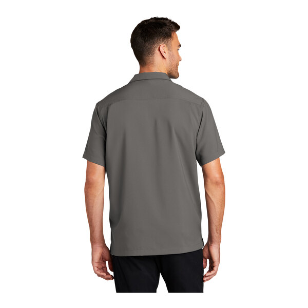 A man wearing a grey Port Authority short sleeved performance staff shirt.