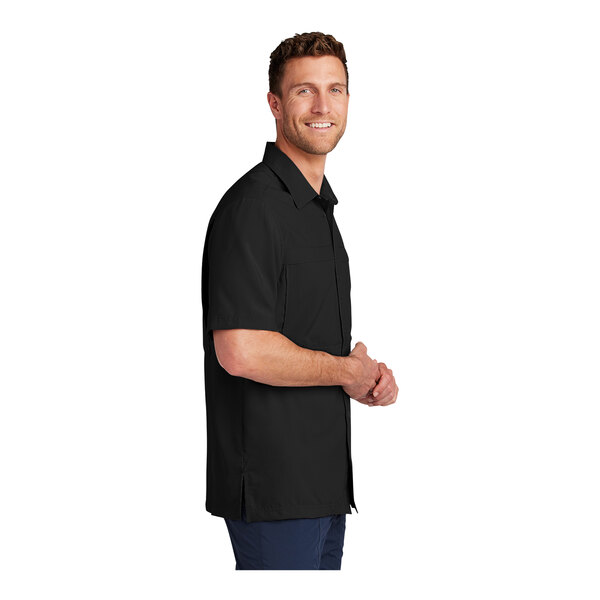 A man wearing a black Port Authority moisture wicking shirt.