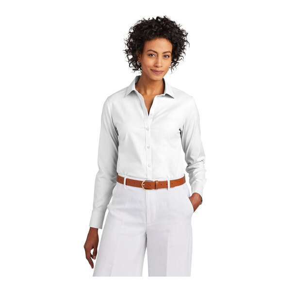 A woman wearing a white Brooks Brothers long sleeve dress shirt and brown belt.