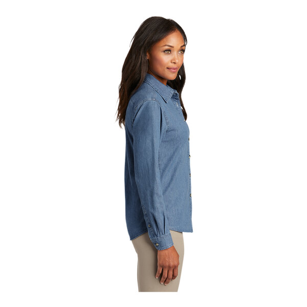 A woman wearing a faded blue Port & Company denim button-down shirt.