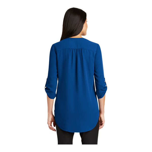 A woman wearing a Port Authority blue short sleeve blouse.