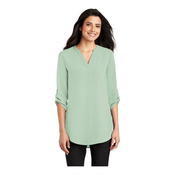 A woman wearing a Port Authority misty sage short sleeve blouse with a v-neck.