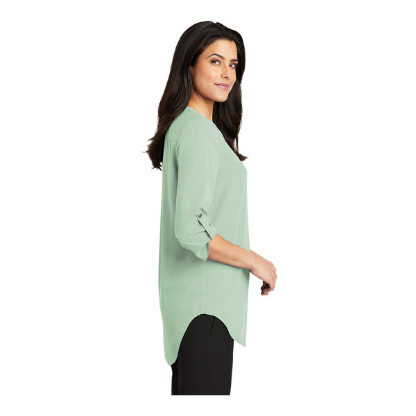 A woman wearing a Port Authority Misty Sage short sleeve blouse.