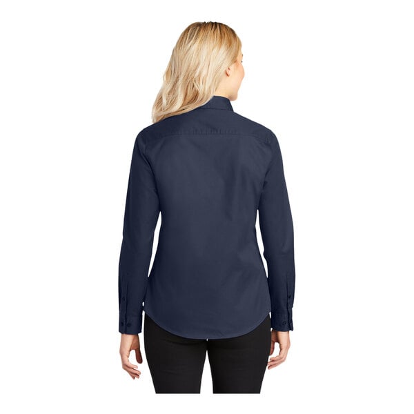 A woman wearing a dark blue Port Authority long sleeve dress shirt.