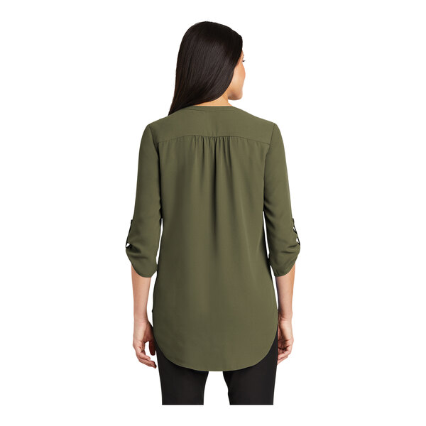 A woman wearing a deep olive short sleeve Port Authority blouse.
