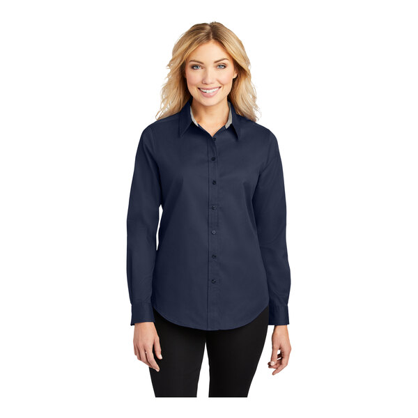A woman wearing a Port Authority navy blue long sleeved dress shirt.