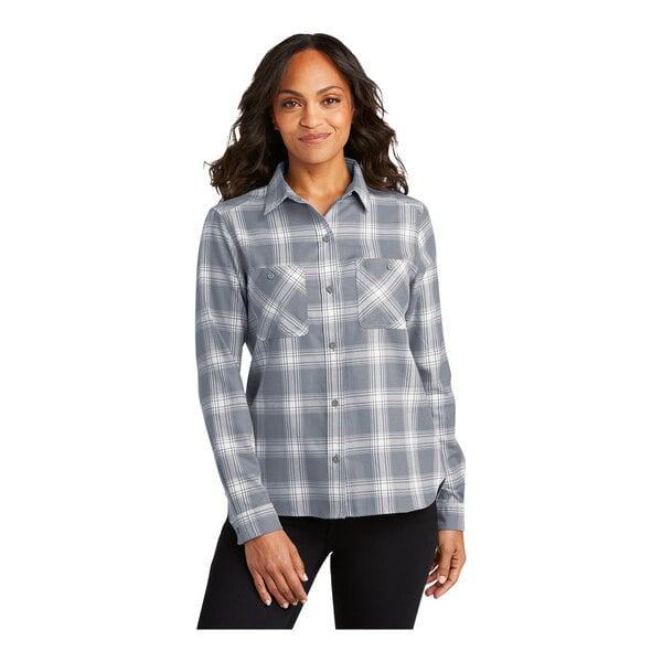 A woman wearing a Port Authority gray and cream plaid flannel shirt with long sleeves.